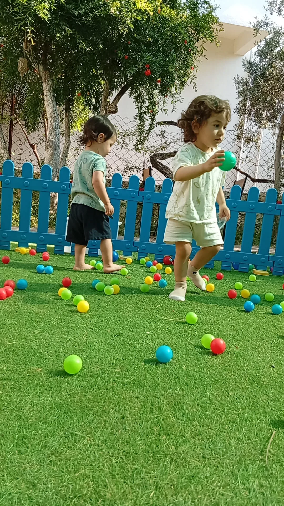 Çitle çevrili çim bahçede oyun oynayan çocuk